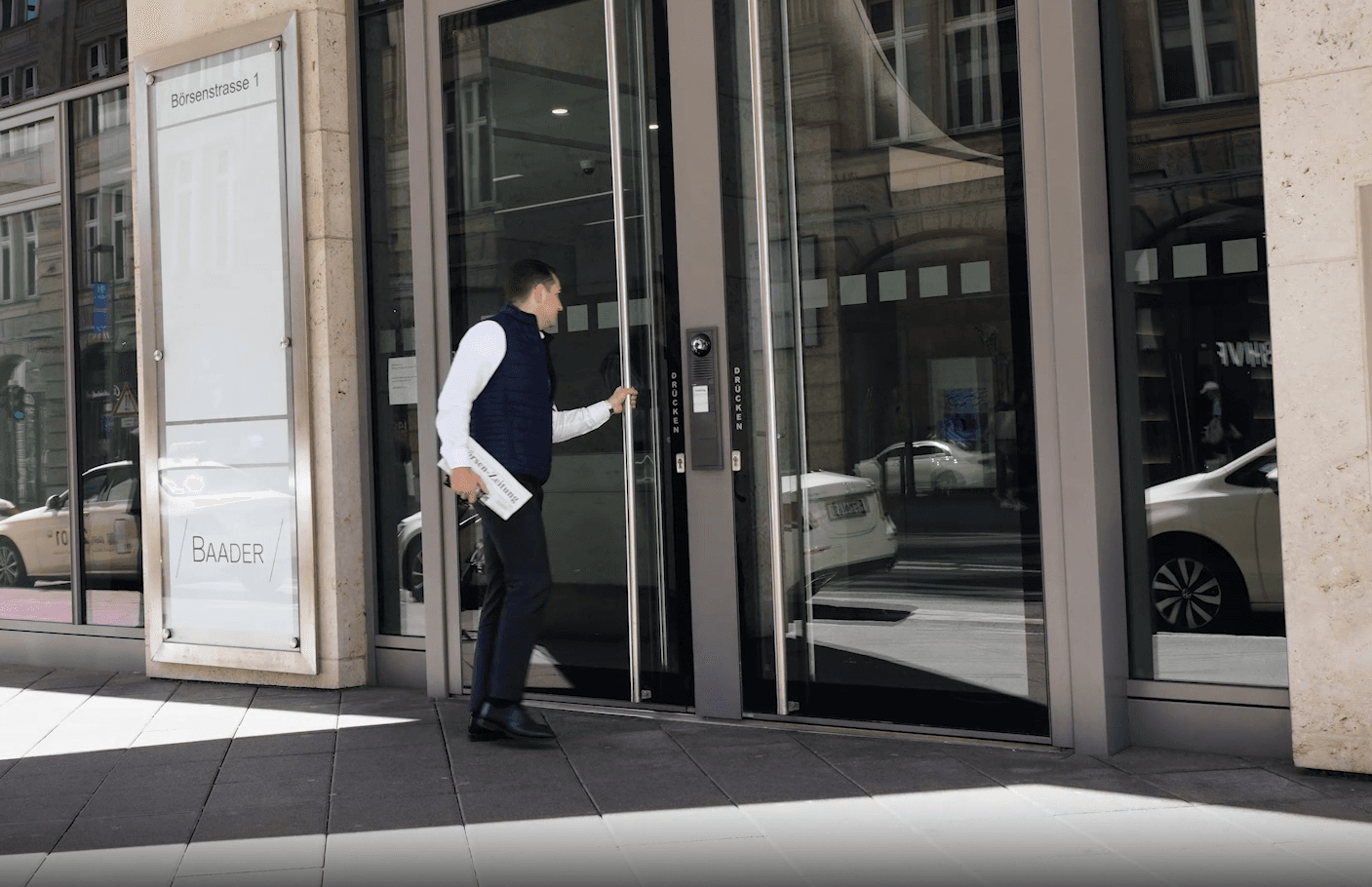 Ein Mann in Businesskleidung betritt durch eine Glastür ein Gebäude an der Börsenstraße 1.